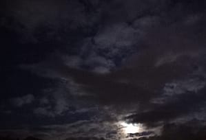 [Justine CM] Ciel de nuit très nuageux, avec la lune qui se montre derrière les nuages.