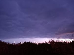 [Justine CM] Ciel d'un bleu teinté de gris et de violet côté front nuageux, qui s'arrête net au loin. Bande plus claire sans nuages ensuite.